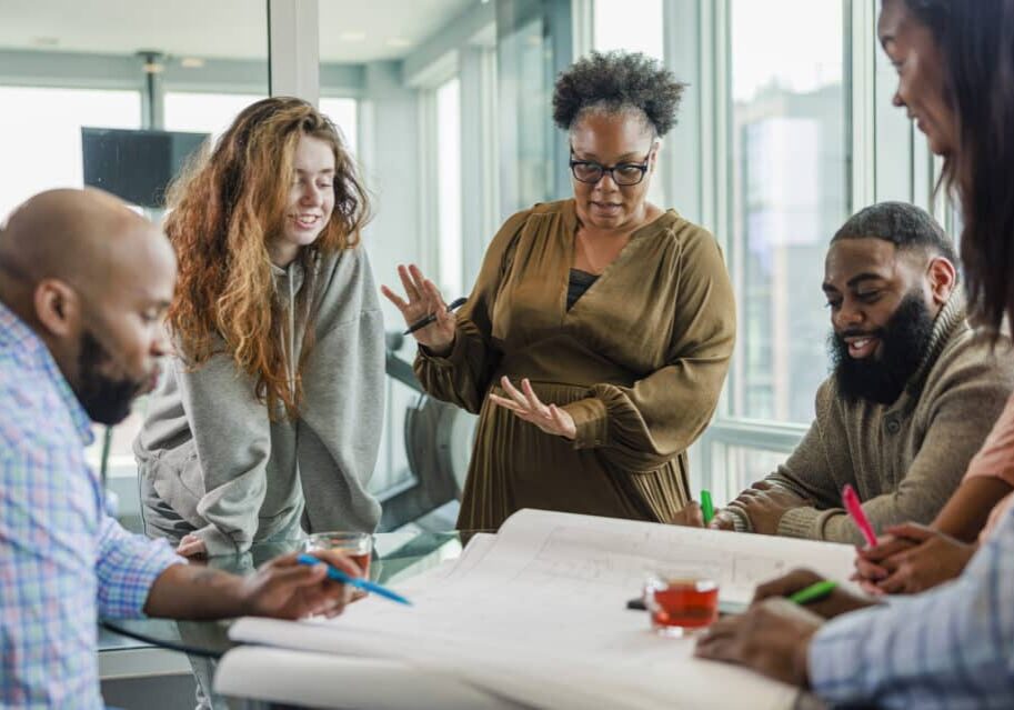 Diverse business partners converse and collaborate with each other during a busy team business meeting.