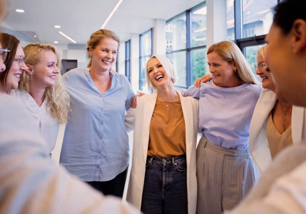 Happy team of female colleagues in huddle during group therapy at office